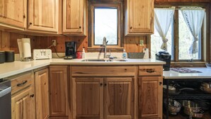 A wooden kitchen with a central island, a sink, and a window with curtains.
