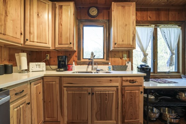 A wooden kitchen with a central island, a sink, and a window with curtains.