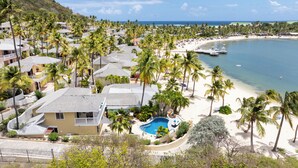 Un quartier résidentiel situé sur la côte, doté d’une piscine, d’une plage et de palmiers.