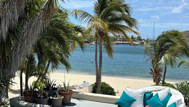 Un espace aménagé au bord de la piscine, avec des sièges disposés en cercle, une piscine et une vue sur la plage et l’océan.