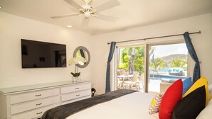 Une chambre avec un lit, une télévision, une commode et une vue sur l’espace extérieur abritant une piscine.