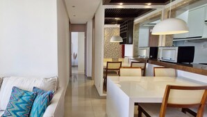 A modern living room with a sofa and a dining area with a table and chairs.