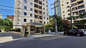 A gated entrance to a residential building with multiple floors, a clear sky, and parked cars.
