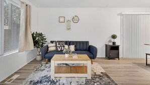 Un salon moderne avec un canapé bleu foncé, une table basse en bois et une plante en pot.