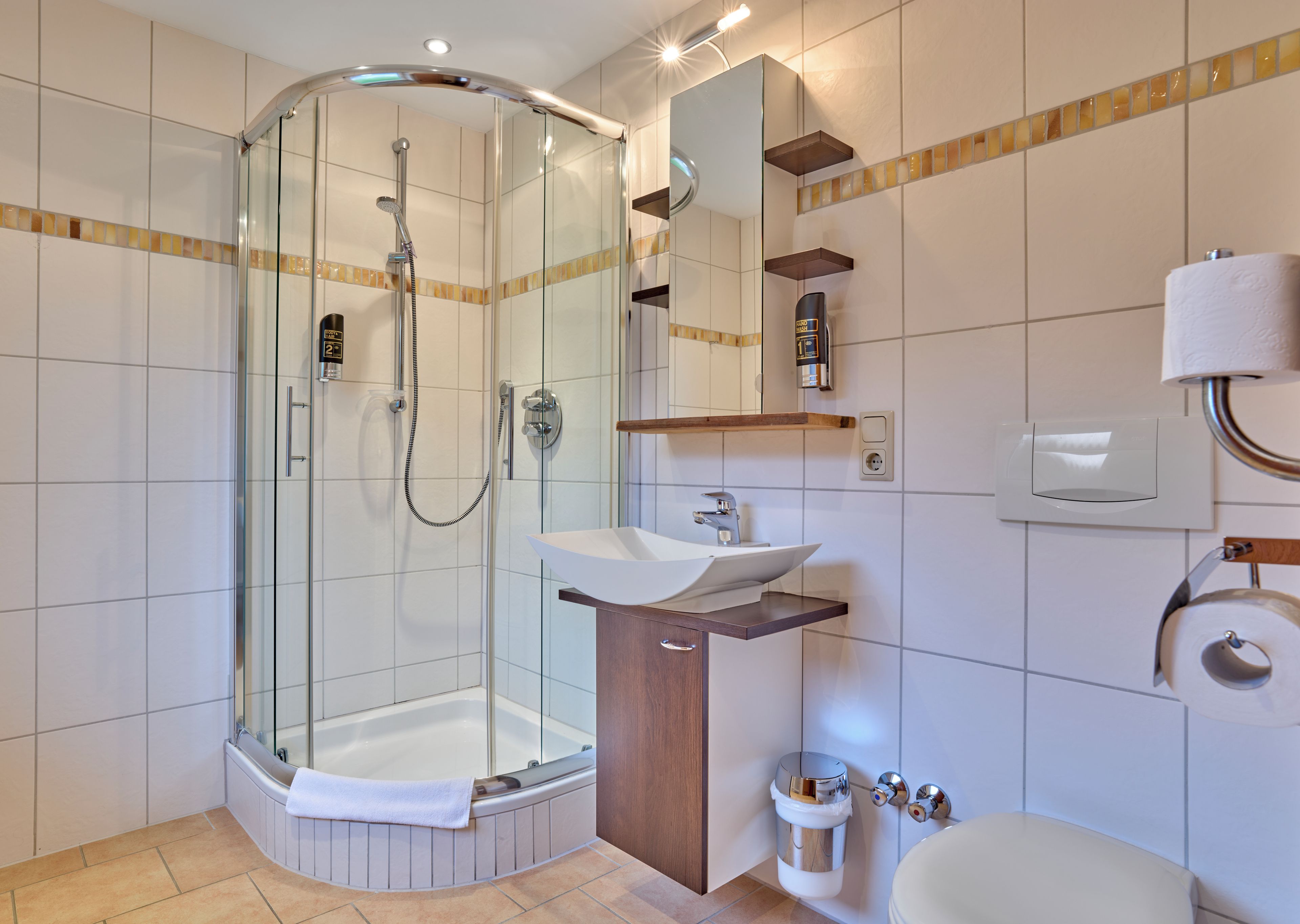 A modern bathroom with a glass-enclosed shower, a sink, and a toilet.