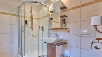 A modern bathroom with a glass-enclosed shower, a sink, and a toilet.