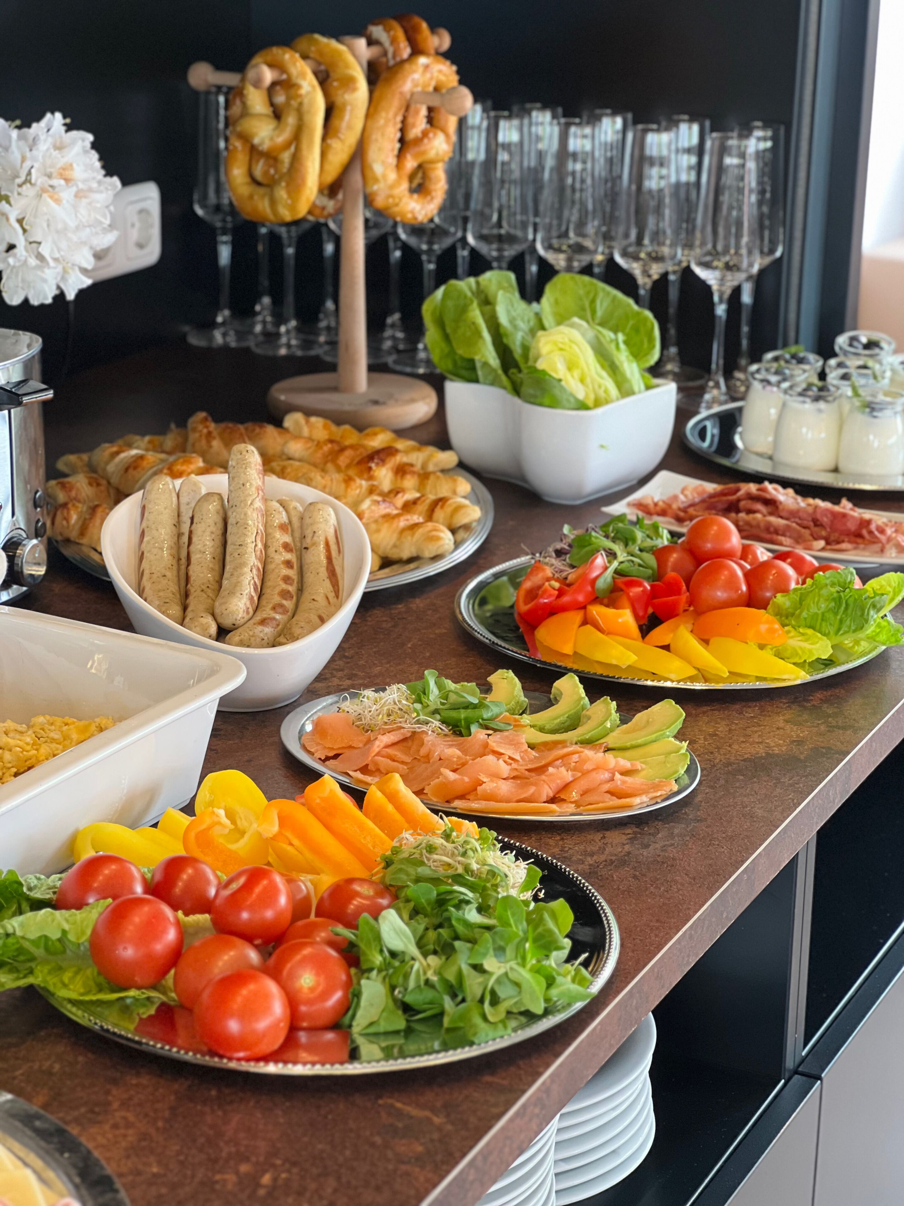A buffet with various food items including sausages, croissants, and salads.