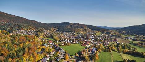 Een landelijk dorp met huizen en velden, omringd door heuvels.
