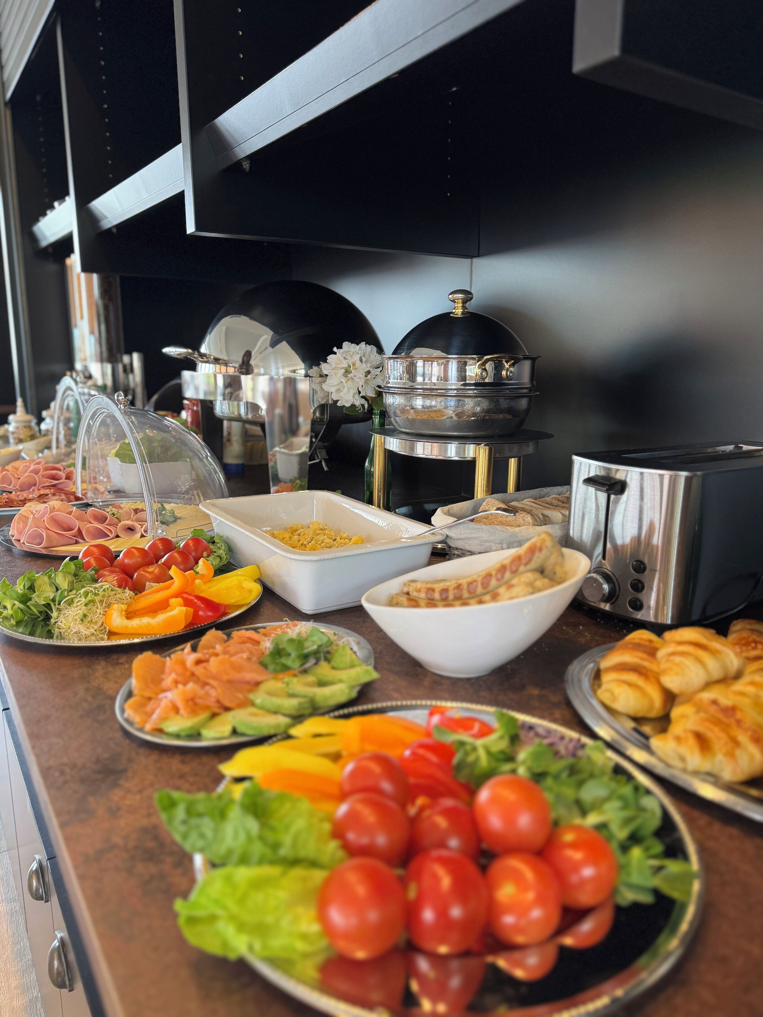 Un bufé con diversas opciones de comida, incluyendo ensaladas, carnes y productos de repostería.