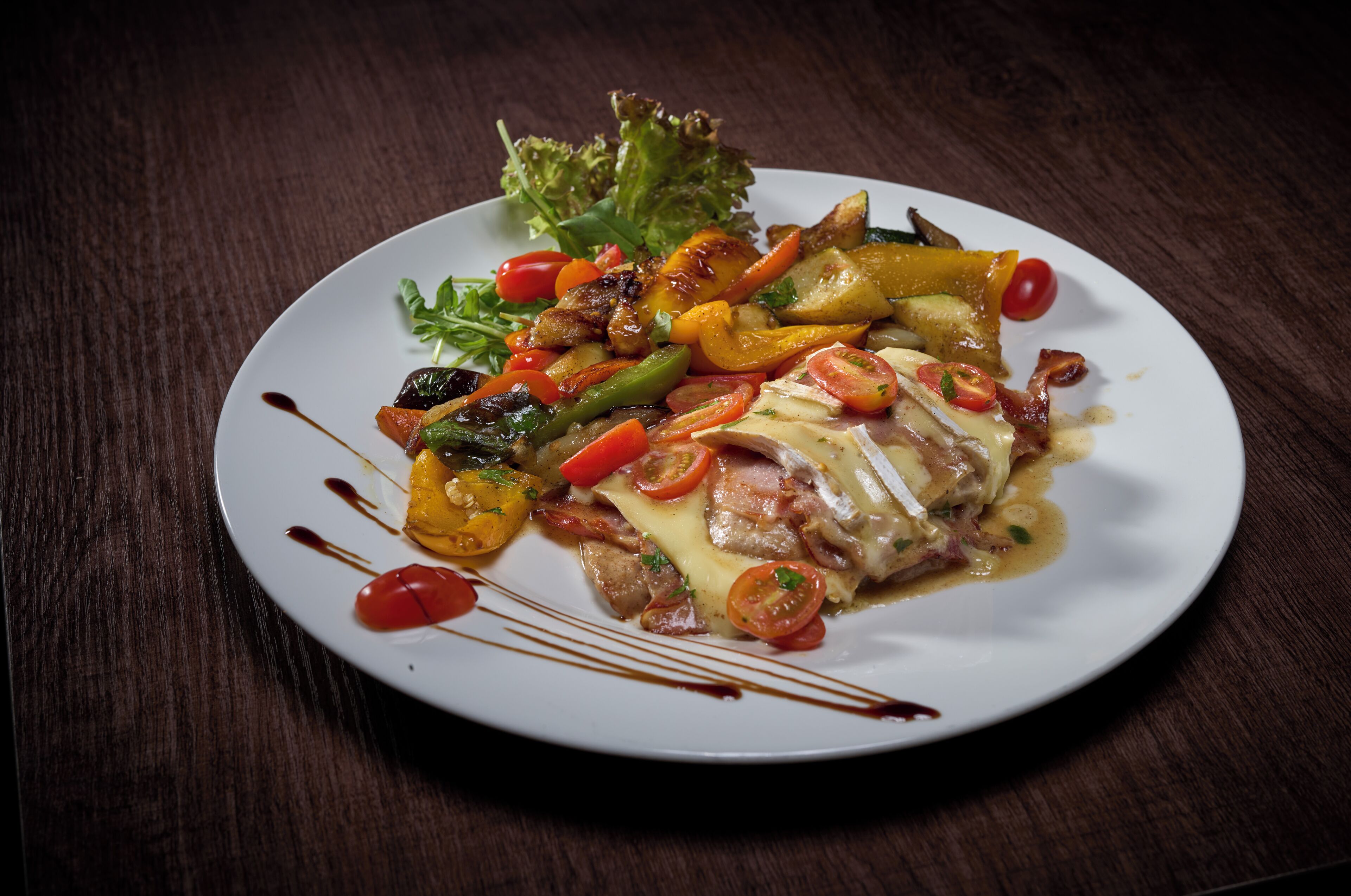A plate of food with various vegetables and meat, garnished with sauce.