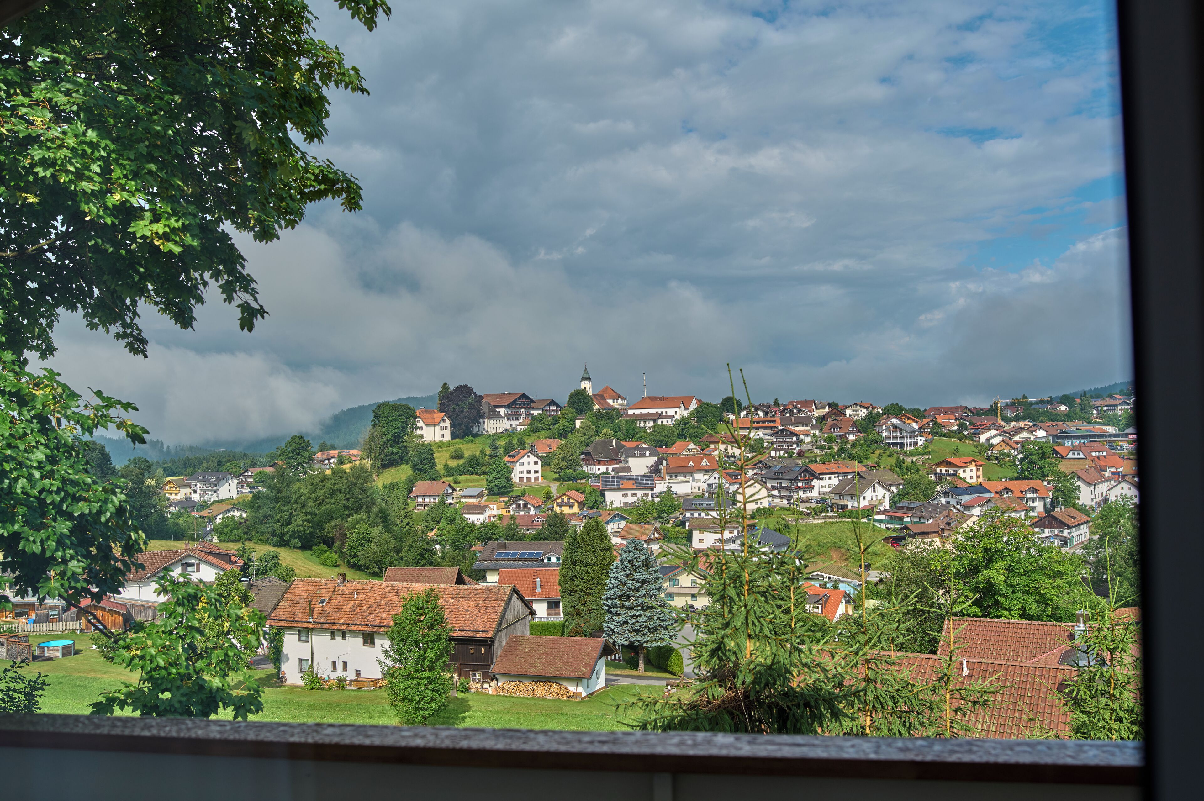 A residential area with houses on a hillside, a church, and a clear sky.