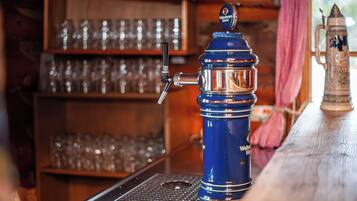 A bar area with a blue beer tap, shelves with glasses, and a rustic wooden counter.