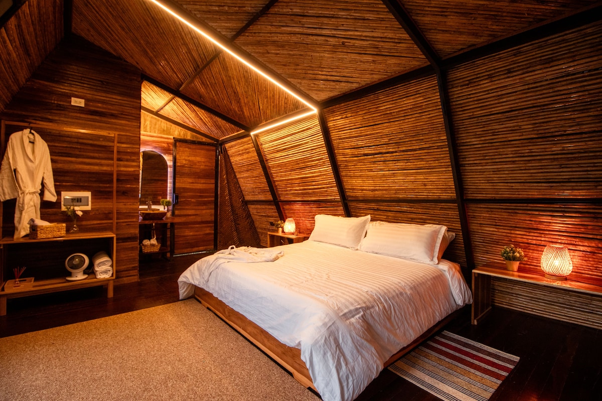 A cozy, wooden-themed bedroom with a large bed, bedside lamps, and a mirror.