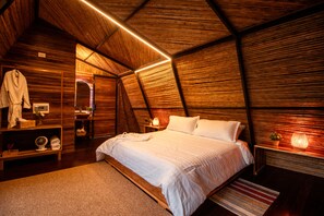 A cozy, wooden-themed bedroom with a large bed, bedside lamps, and a mirror. - Ecolodge Palonegro (Lebrija)