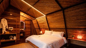 Une chambre à coucher chaleureuse, décorée dans un style rustique avec du bois, comprenant un grand lit, des lampes de chevet et un miroir.