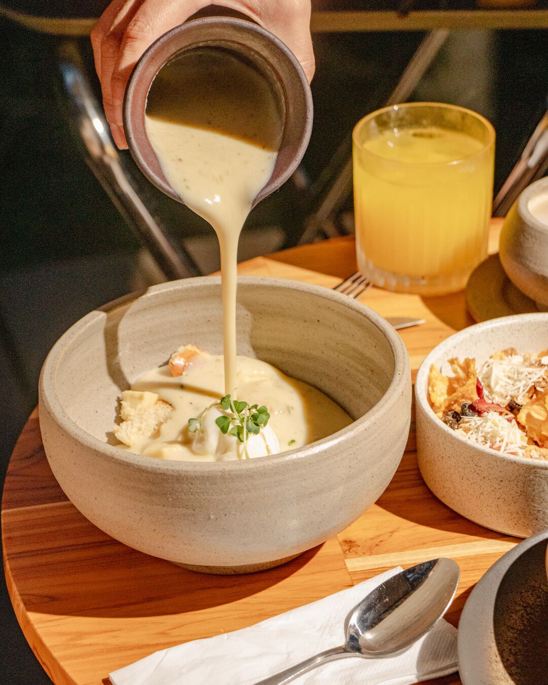 A bowl of soup being poured into a larger bowl.