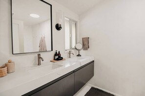 Une salle de bain moderne avec un grand miroir, deux lavabos et un meuble-lavabo.