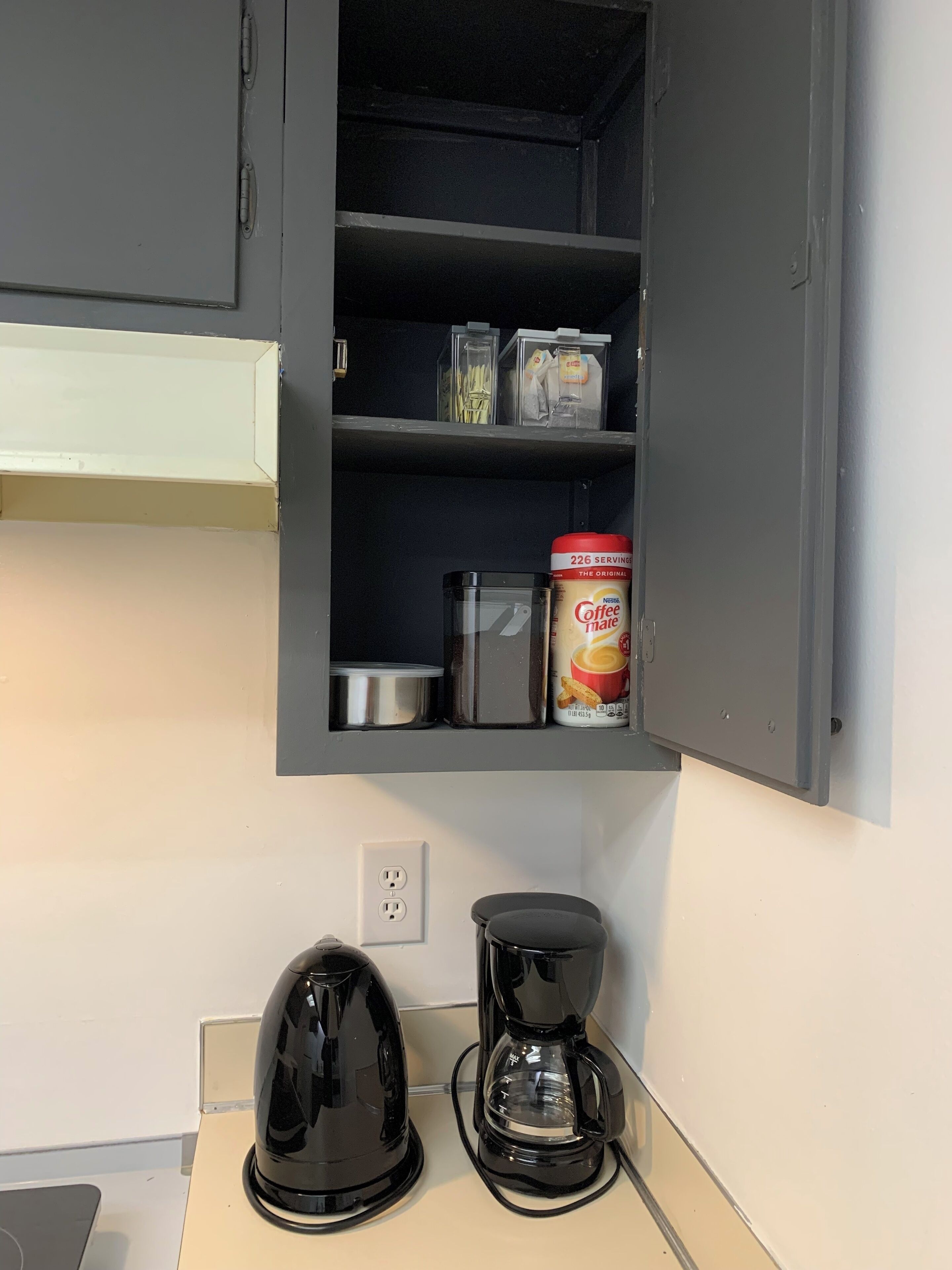 Una cocina con un mueble empotrado que contiene una cafetera, un hervidor y un recipiente.