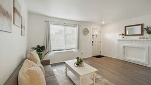 A modern living room with a sofa, a coffee table, a fireplace, and a window with curtains. - Central Bellevue Retreat  (Bellevue)