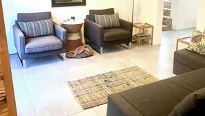 Uma sala de estar com dois sofás, uma mesa de centro, um abajur e arte decorativa nas paredes.