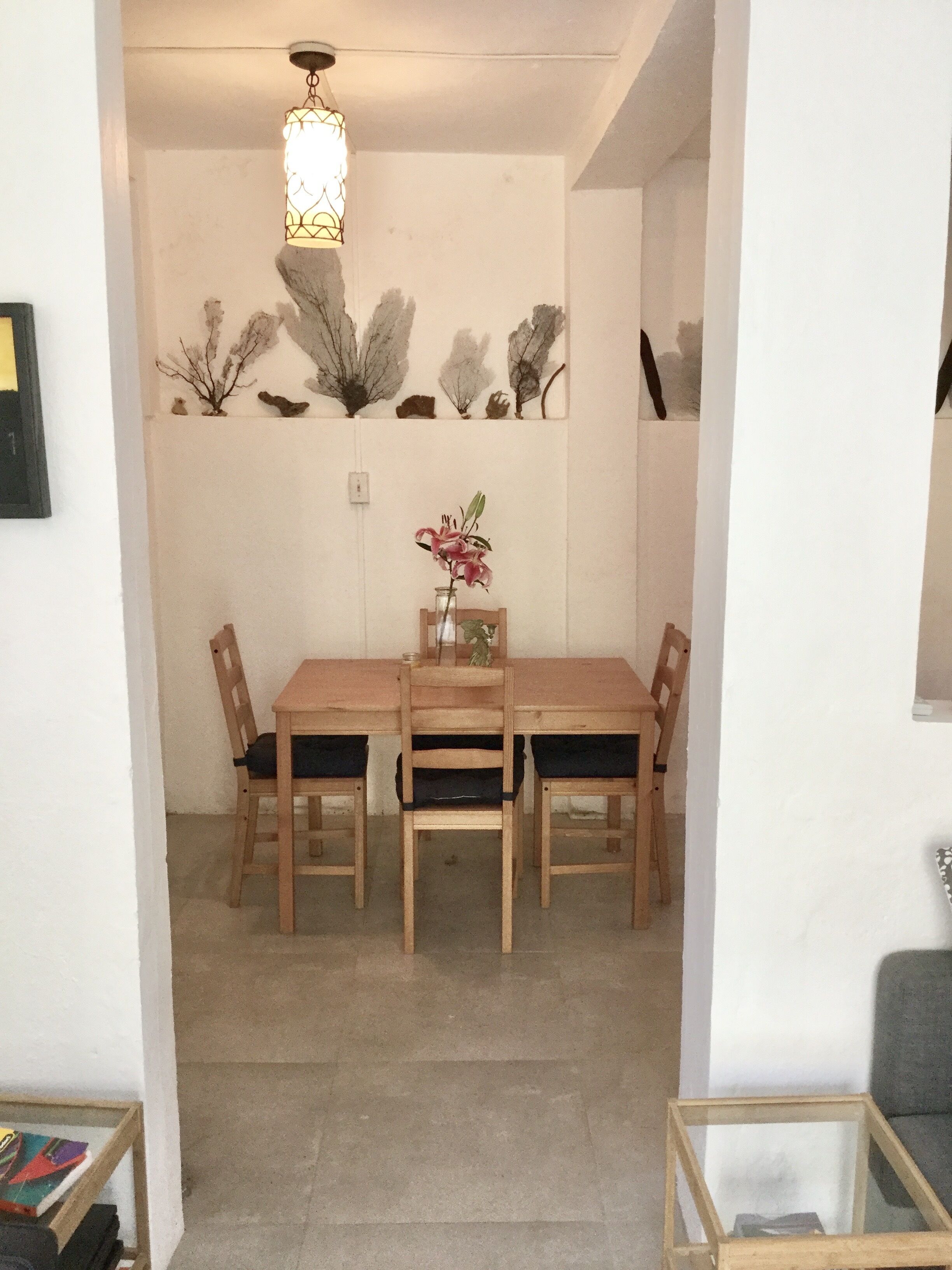 Uma área de refeições com mesa e cadeiras de madeira, um vaso com flores e decorações nas paredes.