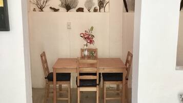 Uma área de refeições com mesa e cadeiras de madeira, um vaso com flores e decorações nas paredes.