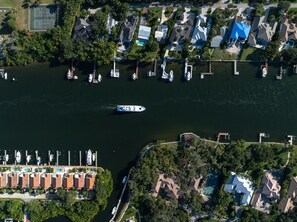 An aerial view of a marina with boats docked, a tennis court, and residential buildings. - Superyacht Bahamas PrivateCruise (Tampa)