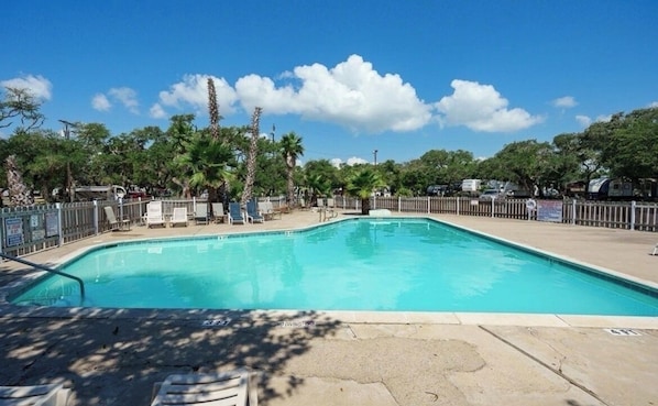 Una piscina rectangular con una solana empaveda alrededor.