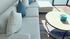 Una sala de estar moderna con un sofá blanco, cojines azules y una mesa de centro redonda.