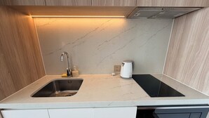 Una cocina moderna con un lavamanos integrado, una tetera y un microondas.