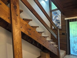A wooden staircase with a handrail and a glass door leading to an outdoor area.