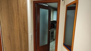 A hallway with a wooden door, a frosted glass door, and a tiled floor leading to a kitchen area. - Apartment Seawolf, Lloret de Mar (Lloret de Mar)