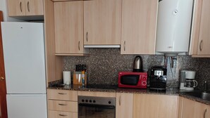 A compact kitchen with wooden cabinets, a white refrigerator, a microwave, a coffee maker, and a stove. - Apartment Seawolf, Lloret de Mar (Lloret de Mar)