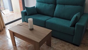 A teal sofa with a wooden coffee table and a white candle. - Apartment Seawolf, Lloret de Mar (Lloret de Mar)