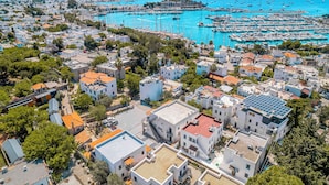 An aerial view of a coastal town with a marina filled with boats, surrounded by residential buildings with flat roofs and solar panels. - NewOld Flat Bodrum Marina 2+1 (Bodrum)