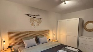 A bedroom with a bed, bedside tables, a wardrobe, and a wall decoration. - NewOld Flat Bodrum Marina 2+1 (Bodrum)