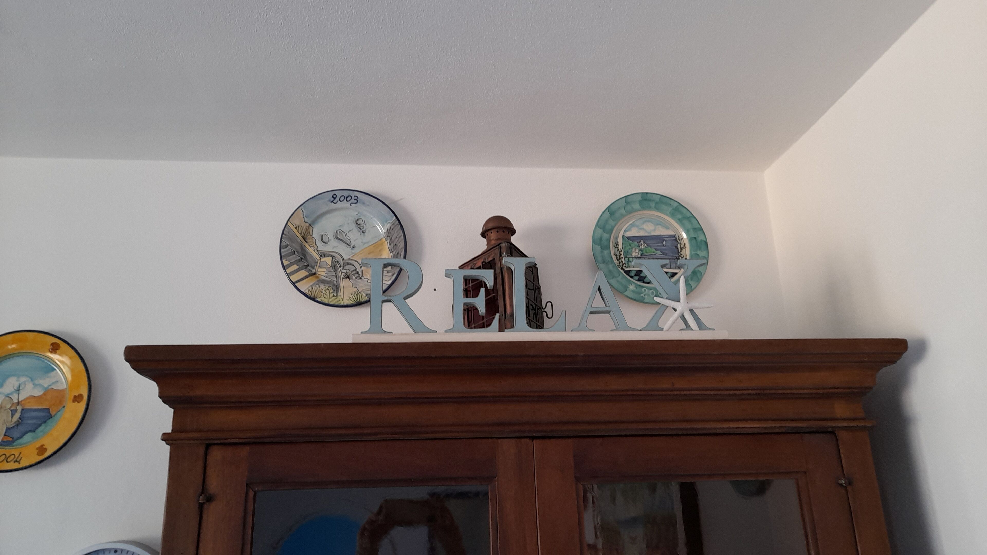 Una pared con placas decorativas y un mueble de madera debajo.