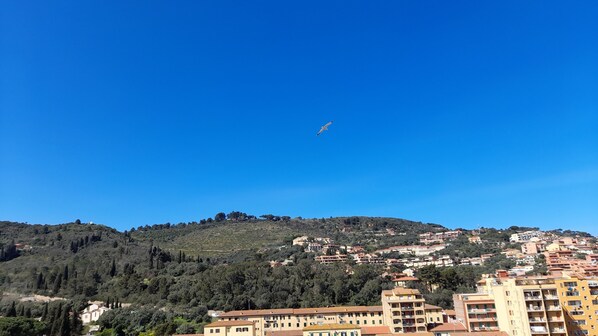 A coastal town with buildings on a hillside and a clear blue sky.