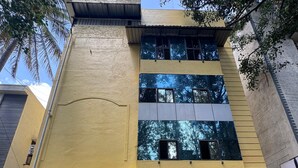 Um edifício de dois andares com fachada amarela, uma placa indicando 