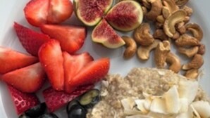 A plate with strawberries, figs, cashews, blueberries, and oatmeal topped with coconut. - Denecrest Guest House (Windermere)