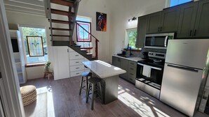 A modern kitchen with a central island, stainless steel appliances, and a staircase leading to another level. - Welcome Home! Cozy, comfortable, quiet, secluded, private, beautiful. (Greenville)