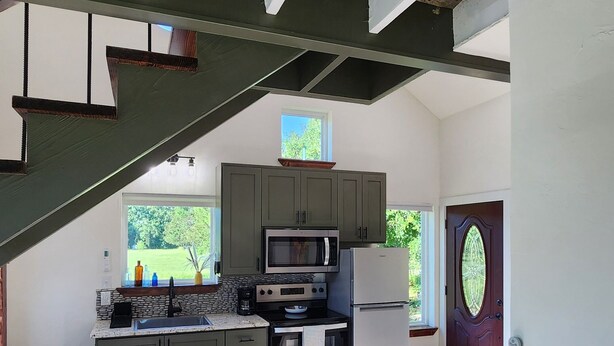 A modern kitchen with a central island, built-in appliances, and a large window providing natural light. - Welcome Home! Cozy, comfortable, quiet, secluded, private, beautiful. (Greenville)
