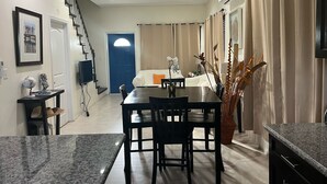 Ein modernes Wohnzimmer mit Essbereich, einer Treppe und einer blauen Tür zu einem anderen Raum.