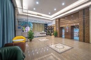 Un vestíbulo de hotel con mostrador de recepción, zona de estar y un gran elemento decorativo en la pared.