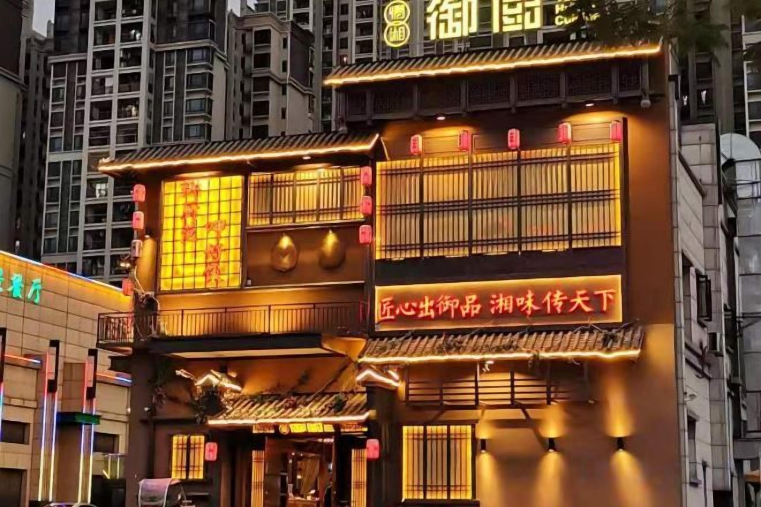 Un edificio tradicional con señalización iluminada y un balcón.