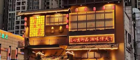 Un edificio tradicional con señalización iluminada y un balcón.