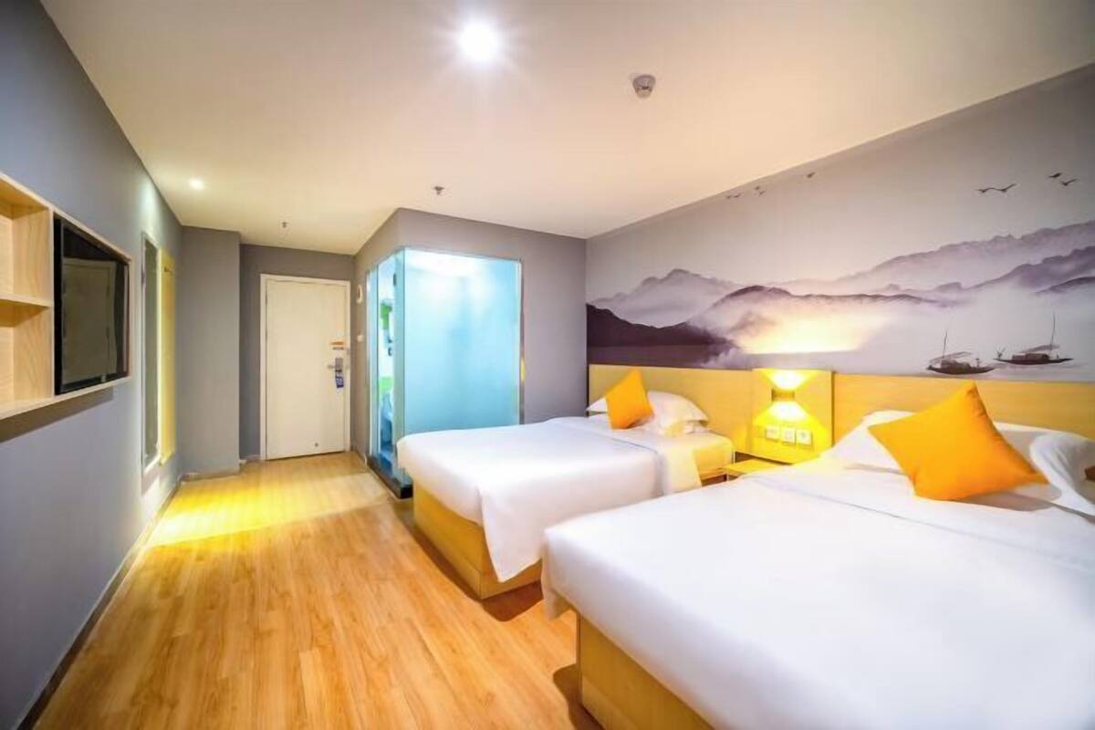 A hotel room with two beds, a mural on the wall, and a wooden floor.