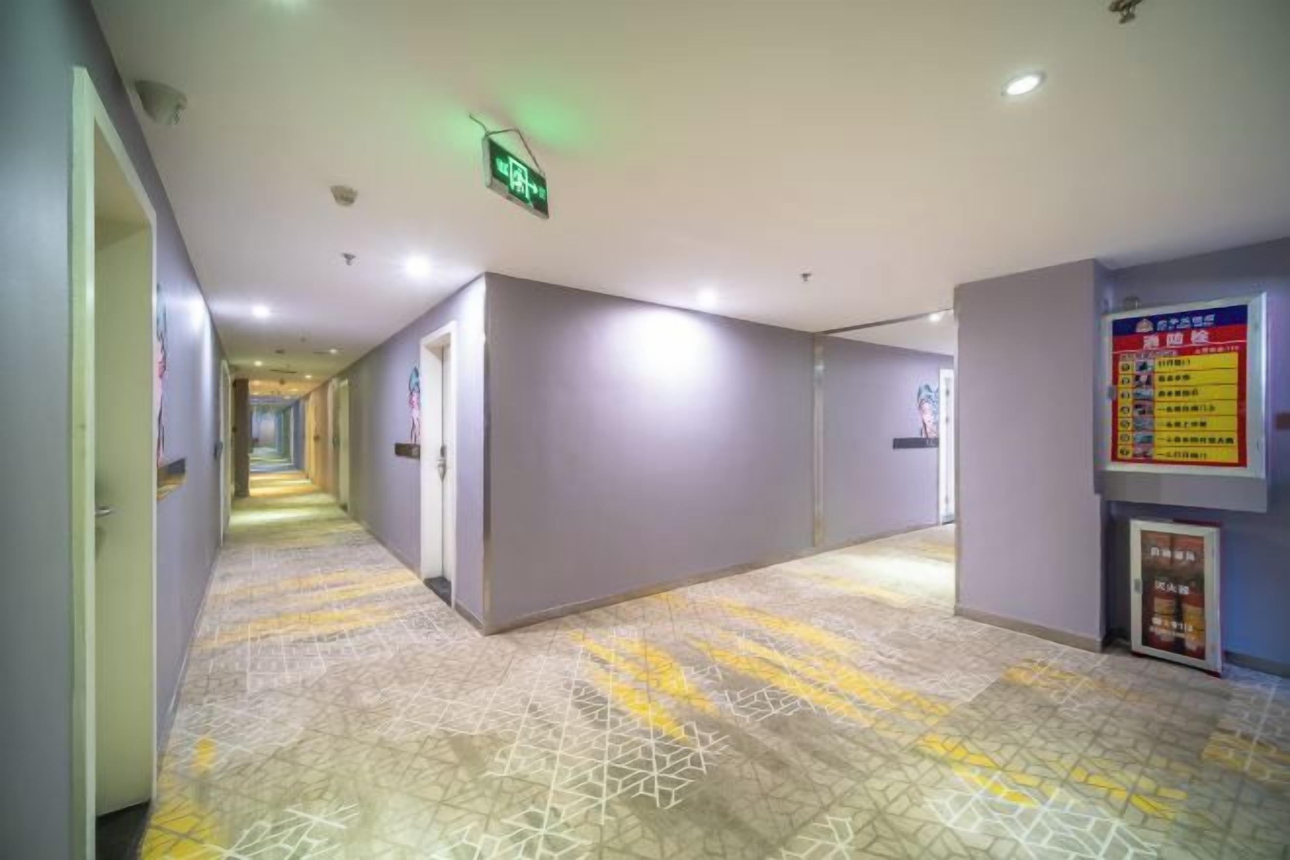 A hotel corridor with a patterned floor, directional signs, and emergency exit signage.