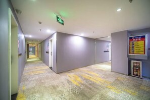 Un pasillo de hotel con suelo estampado, señales de dirección y señalización de salida de emergencia.