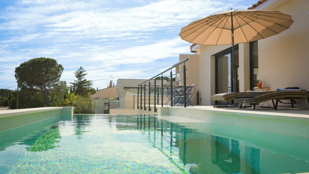 Una piscina con sombrilla, una silla de descanso y una barandilla.